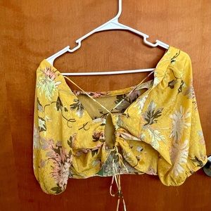 Bella blusa primaveral en estilo crop top con una cinta ajustable atrás.